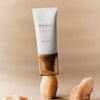Eine Tube Madagascar Centella Air-Fit Suncream Light balanciert auf einem braunen Stein vor einem beigen Hintergrund.