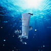 Die Tube schwimmt unter Wasser, ist von Blasen umgeben und wird von blauem Licht von oben beleuchtet.