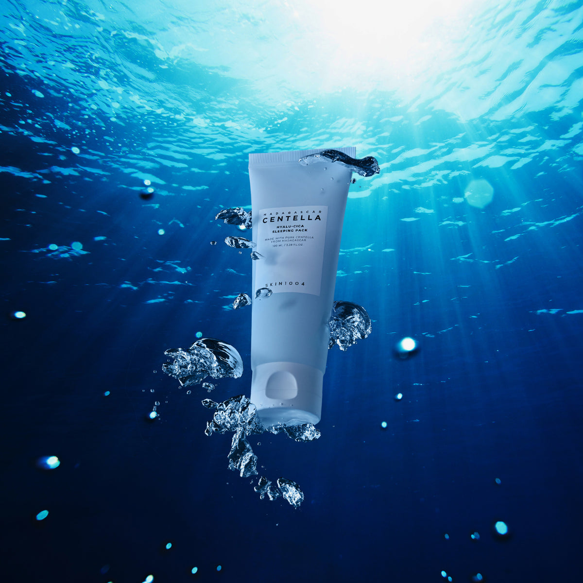 Die Tube schwimmt unter Wasser, ist von Blasen umgeben und wird von blauem Licht von oben beleuchtet.