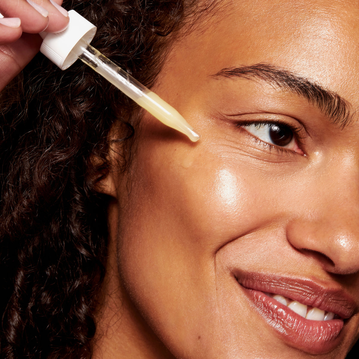 Eine Frau trägt das Timeless Coenzyme Q10 Serum mit einer Pipette auf ihr Gesicht auf. Das gelbliche Serum hat eine leichte, gelartige Konsistenz.