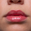 Nahaufnahme von glänzenden, rosa Lippen und einem Teil einer Nase auf glatter, heller Haut.