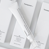 Eine weiße Tube P.I.E Acne Red Spot Fading Treatment, liegt schräg auf drei Verpackungen auf weißem Hintergrund.