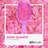 Kleine Bürste des UNbrush Glitter Duo Set Rose Quartz Pink auf Rosenquarzsteinen abgebildet.