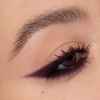 Nahaufnahme eines Auges mit dramatischem burgunderfarbenem Eyeliner und definierten Wimpern, erstellt mit Cupid’s Arrow Longwear Stylo.