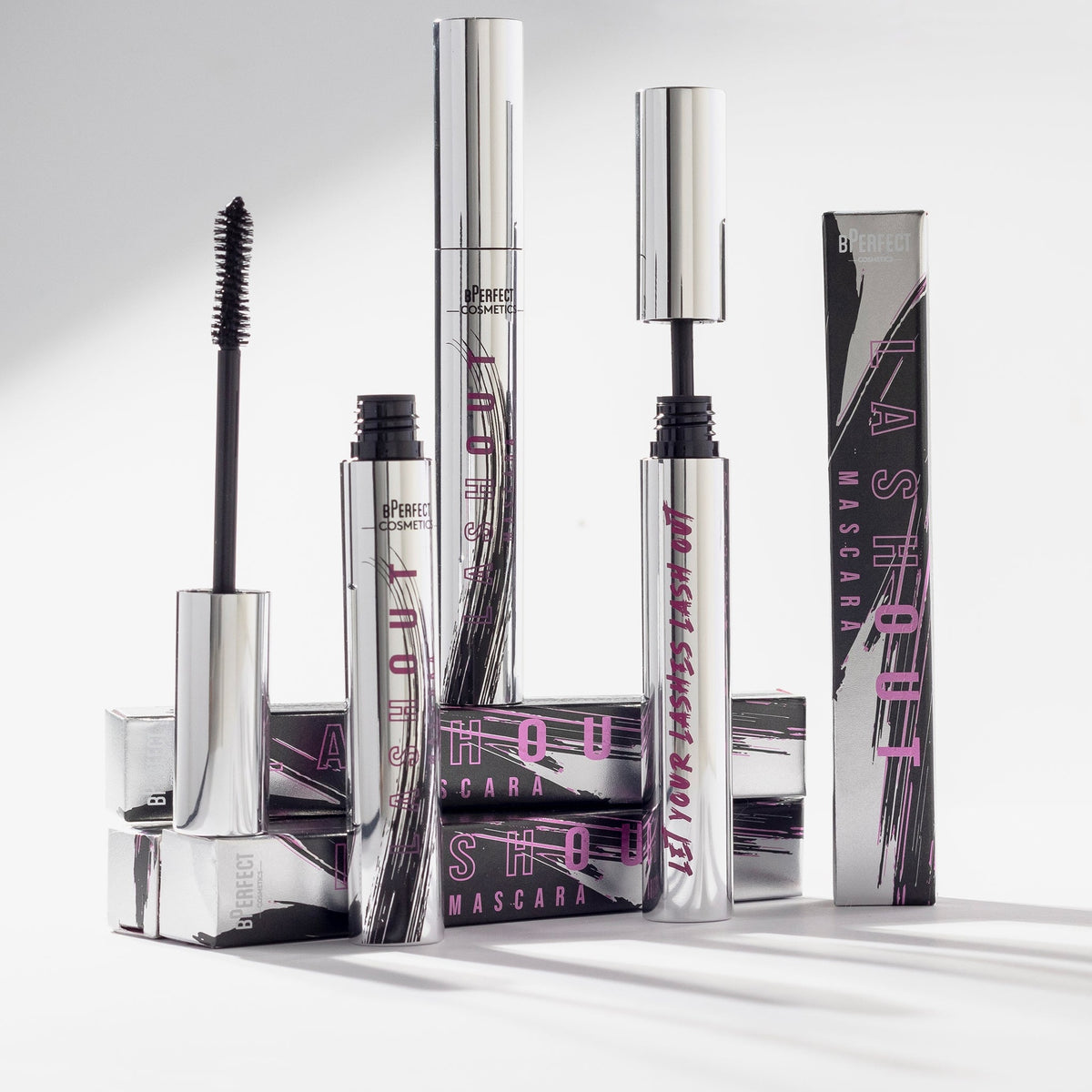 Mehrere Lash Out Mascaras und deren Verpackungen vor einem hellen Hintergrund.