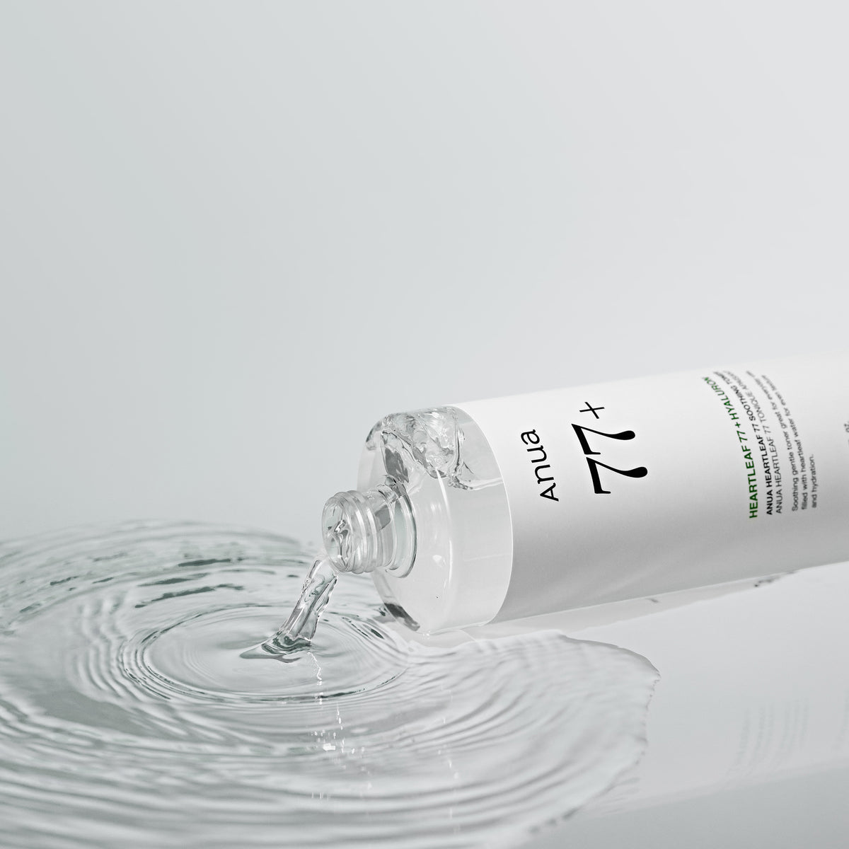 Aus einer Flasche Heartleaf 77 % Soothing Toner wird Flüssigkeit auf eine glatte Oberfläche gegossen, wodurch sanfte Wellen im Wasser entstehen.