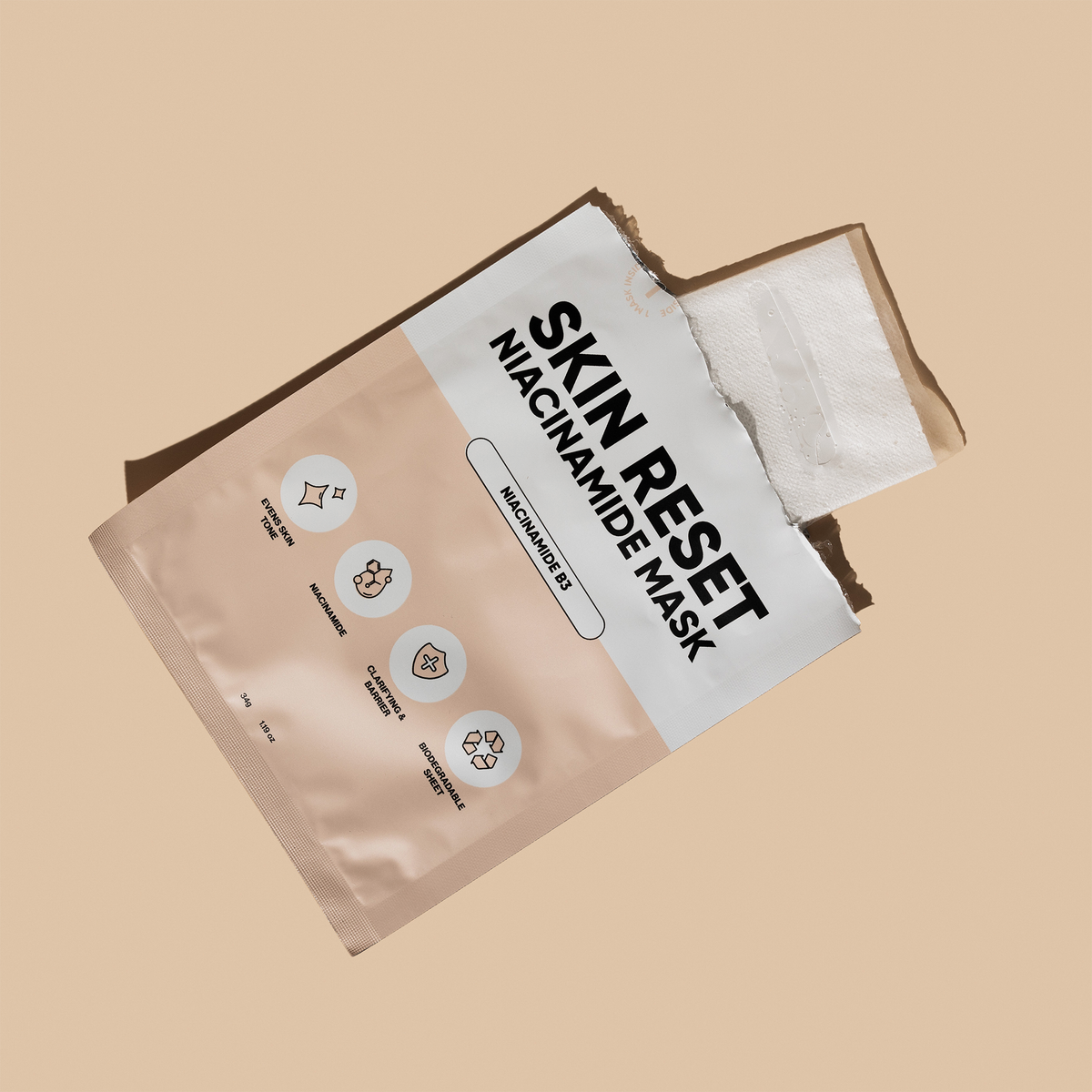 Aufgerissenes Päckchen einer Breakout+Aid Skin Reset Niacinamide Mask mit Symbolen für Hautton, Hautbarriere und biologisch abbaubares Maskenblatt.