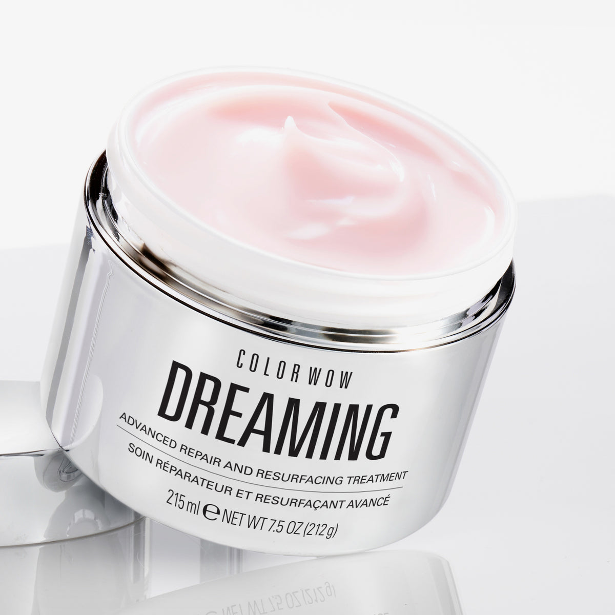 Ein geöffneter Tiegel Color Wow Dreaming Treatment enthüllt eine rosafarbene Creme, die auf einer weißen Fläche präsentiert wird.