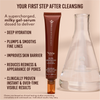Eine Tube Yummy Skin 10/10 Barrier Boost von Danessa Myricks Beauty steht aufrecht neben einer Glasflasche, deren Vorteile auf einem beigen Hintergrund hervorgehoben sind.