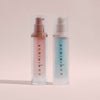 Zwei Dominique Moisture Grip Serum Primer-Flaschen mit Pumpspender, eine mit rosa Flüssigkeit und eine mit blauer Flüssigkeit gefüllt.