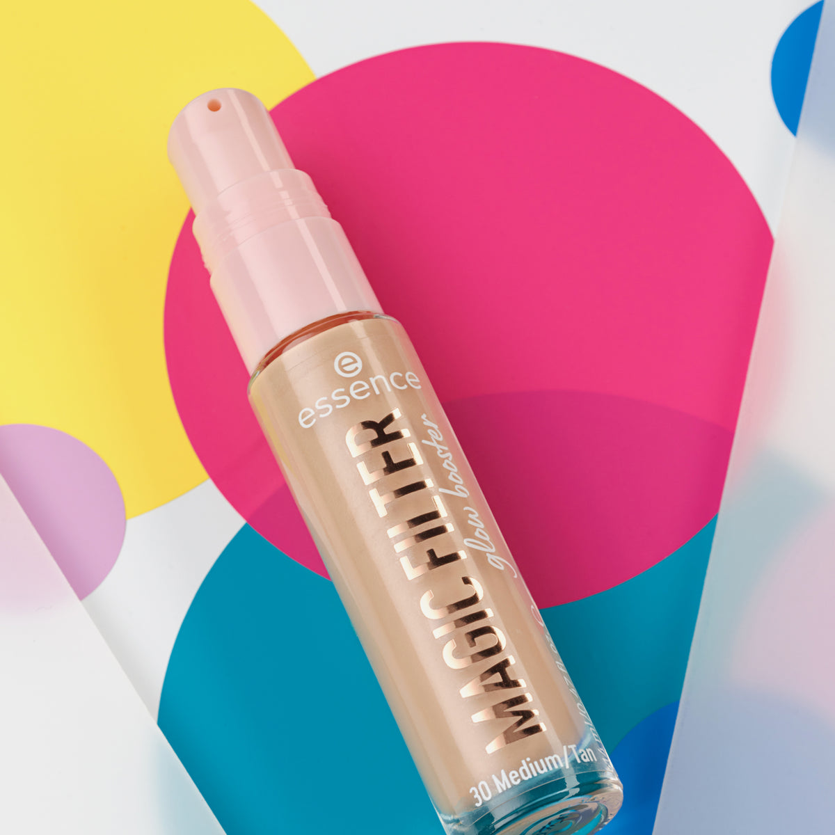 Eine Flasche MAGIC FILTER Glow Booster 30 Medium/ Tan liegt auf einem bunten geometrischen Hintergrund.