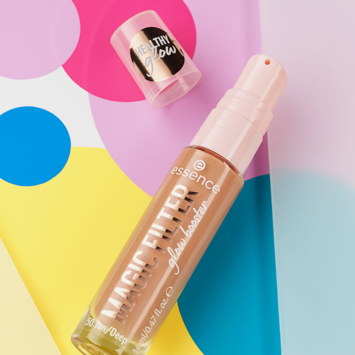 Eine offene Flaschen MAGIC FILTER Glow Booster 50 Tan / Deep liegt auf einem bunten geometrischen Hintergrund.