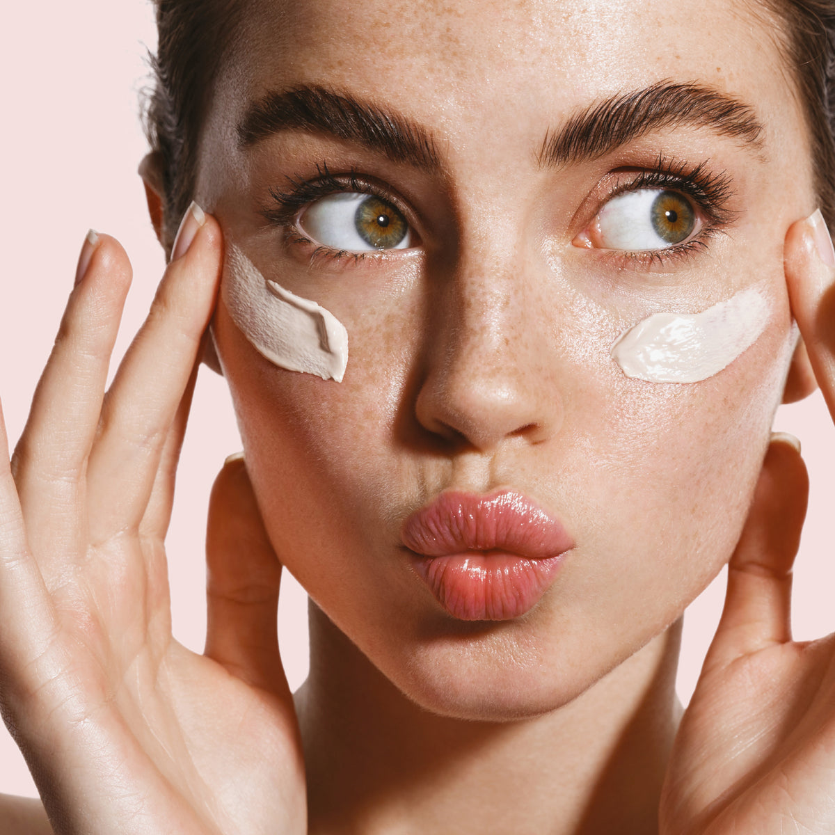 Eine Frau, die HUSH Multi-Purpose Moisturiser unter den Augen aufgetragen hat, berührt sanft ihr Gesicht und blickt zur Seite.