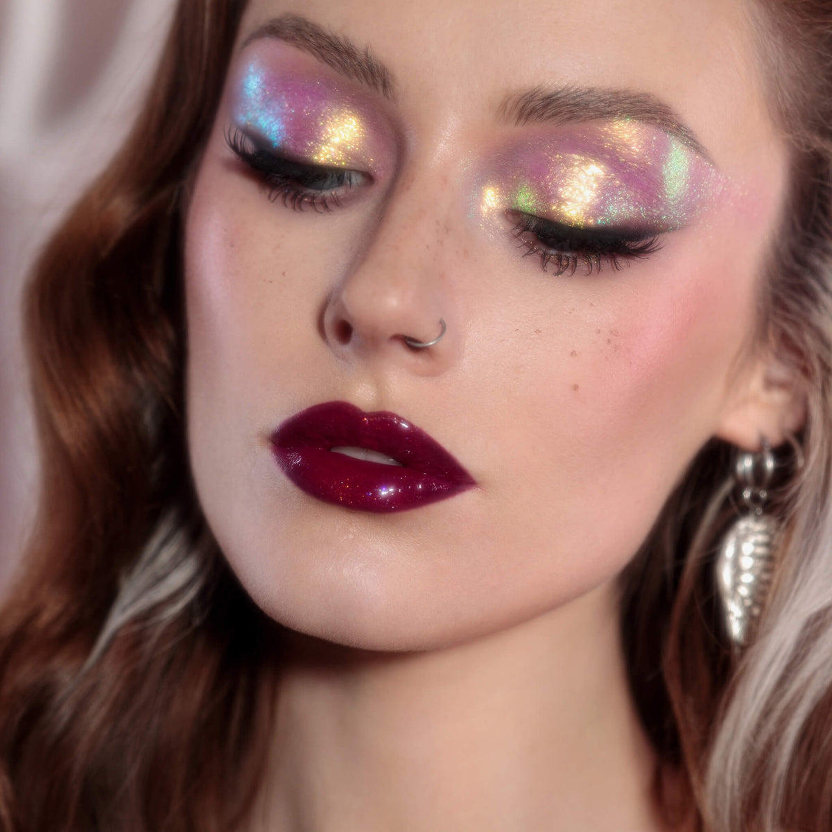 Frau mit dramatischem Eyeliner und glänzenden dunkelroten Lippen trägt rosa-gold schimmernden Opal Moonstone Loose Multichrome Eyeshadow in Boujee Bae auf den Augen.