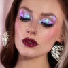 Frau mit dramatischem Eyeliner und glänzenden dunkelroten Lippen trägt lila und blau schimmernden Opal Moonstone Loose Multichrome Eyeshadow in Moody Cow auf den Augen.