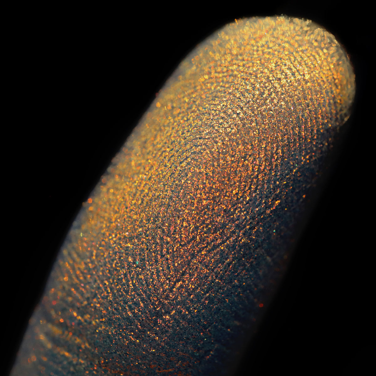 Nahaufnahme einer Fingerspitze, die in den Opal Multichrome Loose Eyeshadow Candlelight getaucht wurde und gelb-gold und orange glitzert.