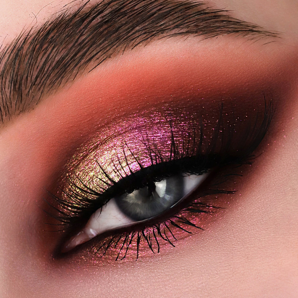 Nahaufnahme eines Auges mit dramatischem Eyeliner und gold-rosa schimmerndem Opal Multichrome Loose Eyeshadow in Romance.