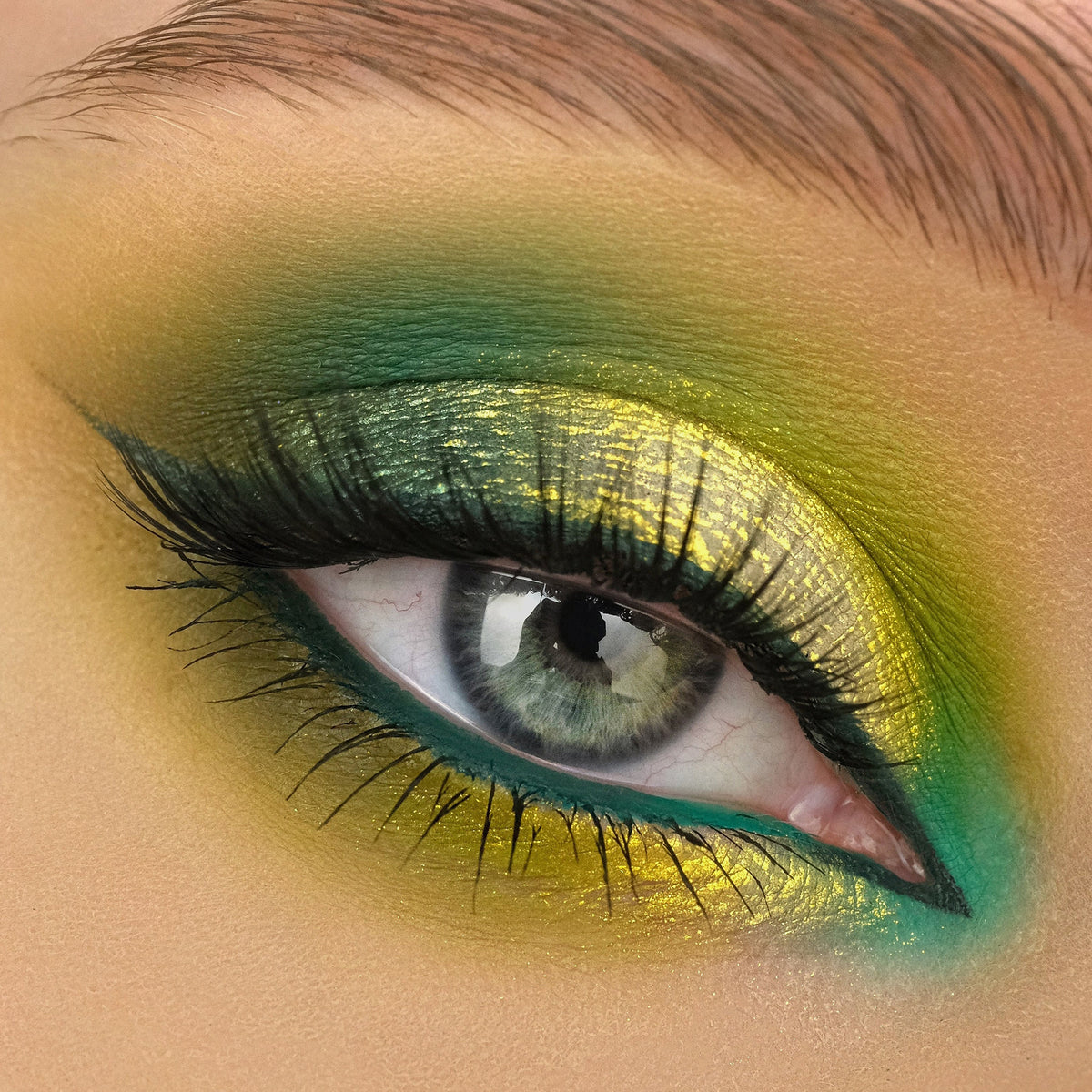 Nahaufnahme eines Auges mit dramatischem Eyeliner und gelb-grünlich schimmerndem Opal Multichrome Loose Eyeshadow in Shooting Star.