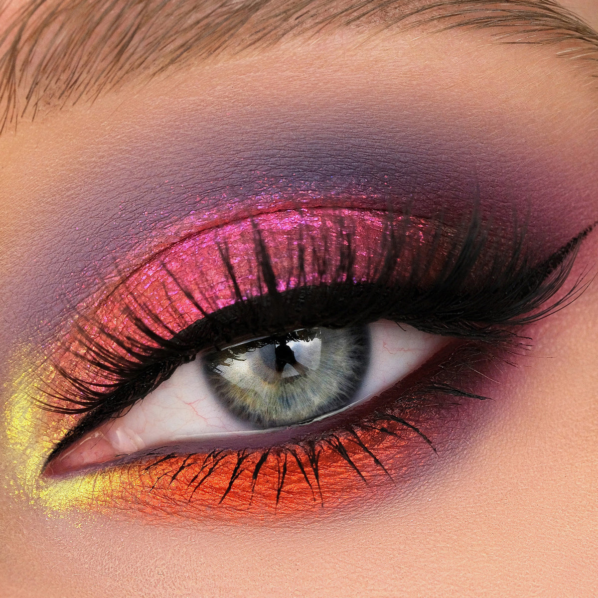 Nahaufnahme eines Auges mit dramatischem Eyeliner und pink-rot schimmerndem Opal Multichrome Loose Eyeshadow in Skylight.