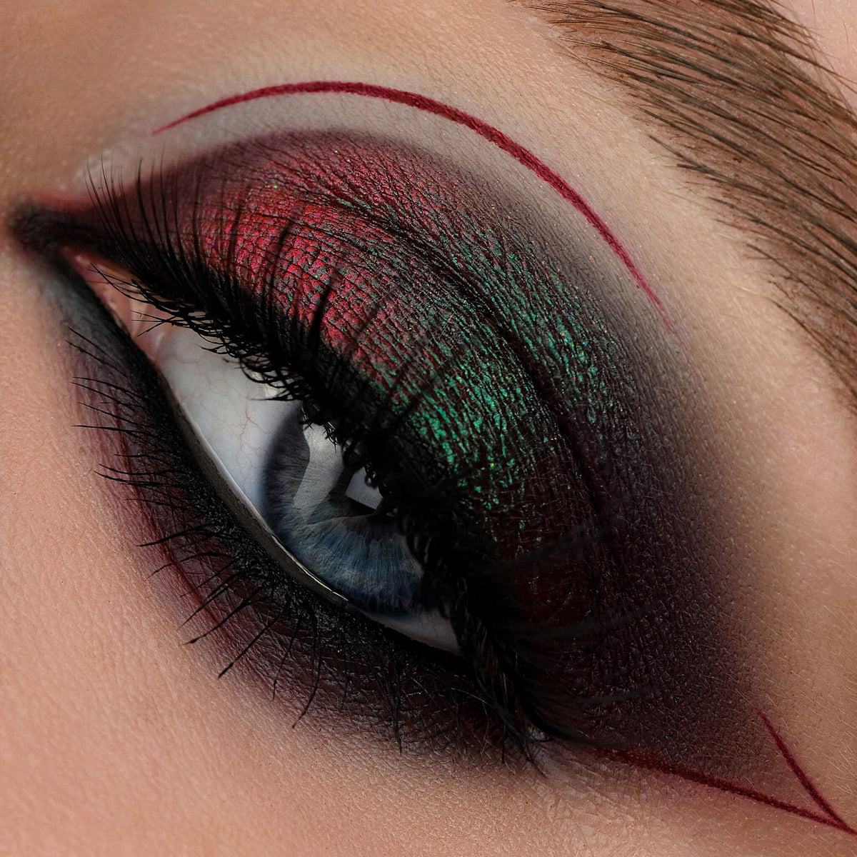 Nahaufnahme eines Auges mit dramatischem Eyeliner und grünlich-rot schimmerndem Original Multichrome Loose Eyeshadow in Lights Out.