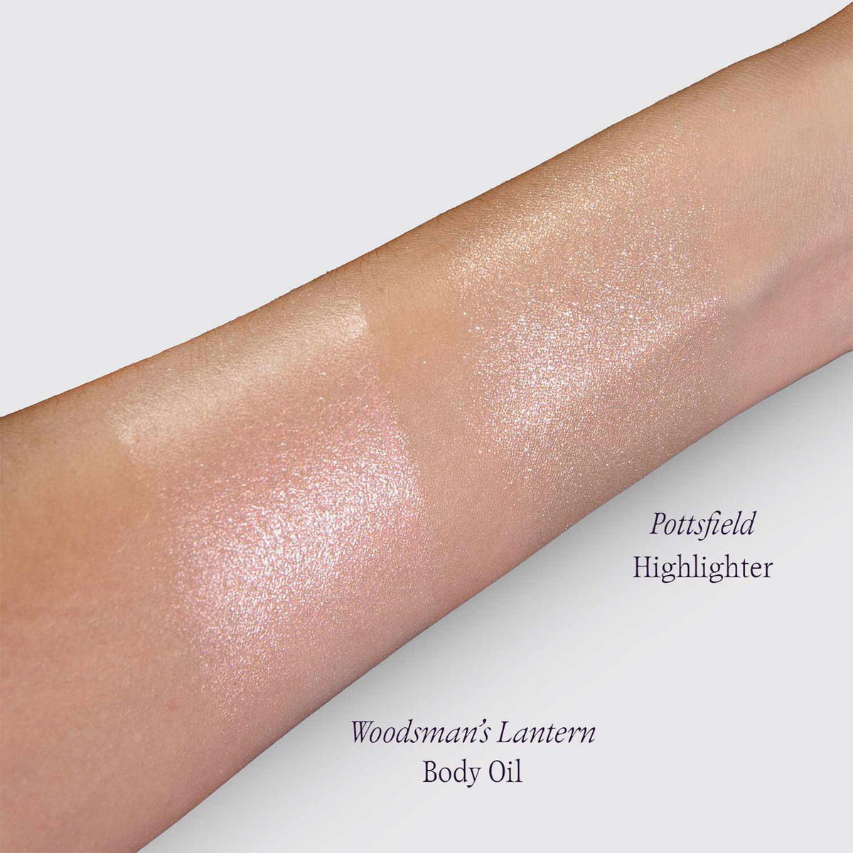 Auf einem Arm sind zwei schimmernde Farbmuster zu sehen: der „Pottsfield Highlighter“ und das „Woodsman’s Lantern Shimmering Body Oil“ von Lethal Cosmetics.