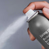 Eine Hand drückt auf die Düse einer Dose Living Proof Perfect Hair Day Dry Shampoo, wodurch ein feiner Nebel freigesetzt wird.