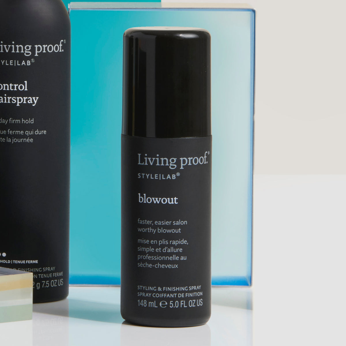 Eine Flasche Living Proof Style Lab Blowout steht vor blauem Objekt.