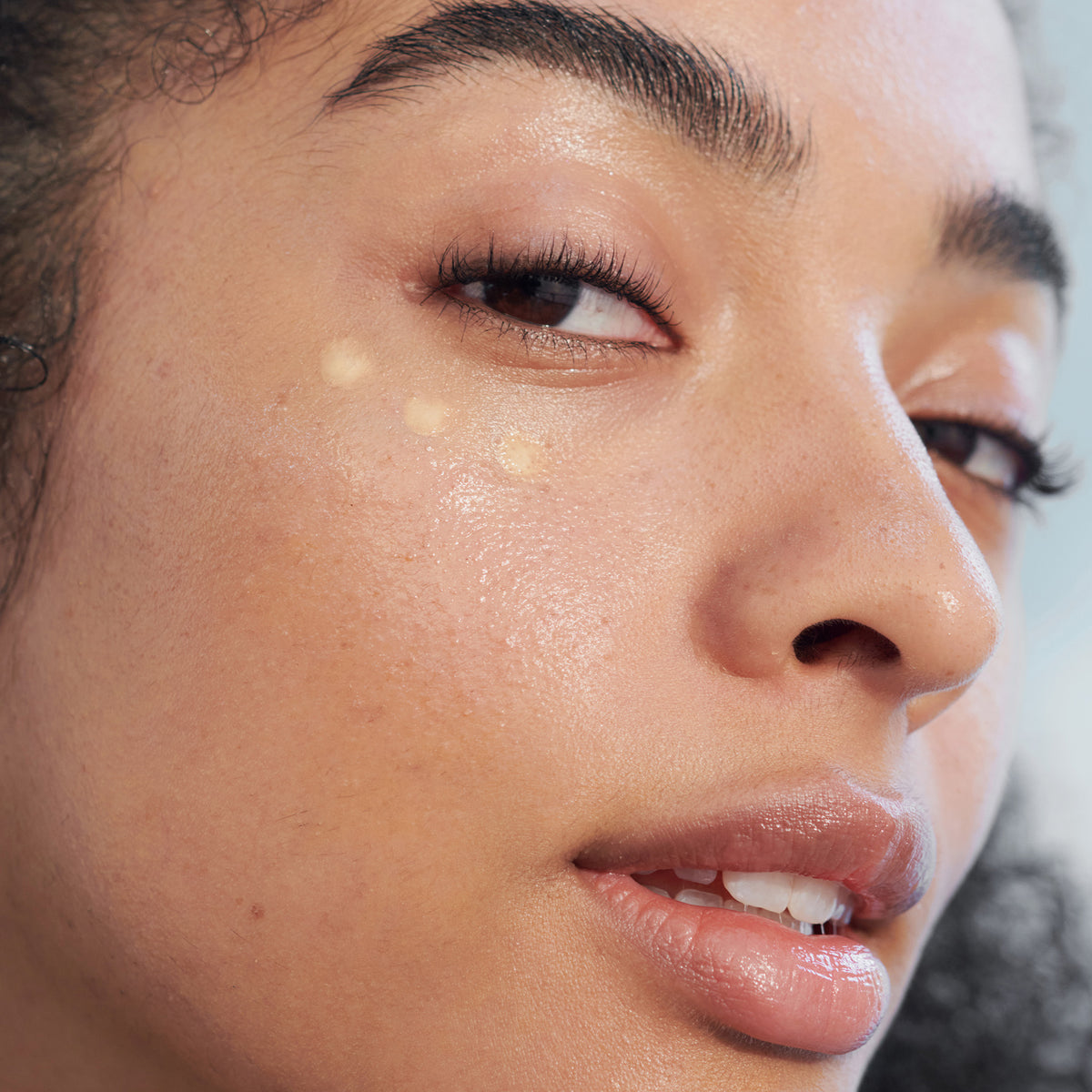 Nahaufnahme des Gesichts einer Frau mit drei Punkten des Lumene NORDIC-C [VALO] Glow Boost Eye Serum unterm Auge.