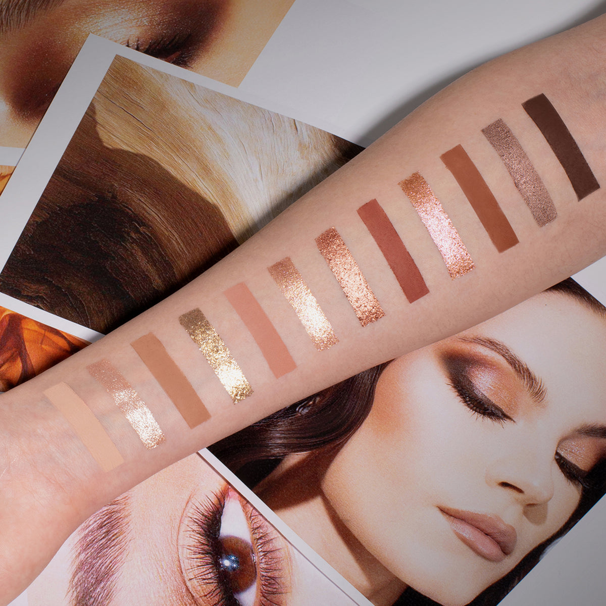 Auf einem Arm sind Lidschattenswatches der ARCHETYPE II zu sehen; darunter Editorial Fotos auf einem Tisch.