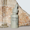 Eine Flasche NERDS. Hyperpigmentation Serum mit einer Pipette ist vor einem Stein und einem Glasmesszylinder ausgestellt.