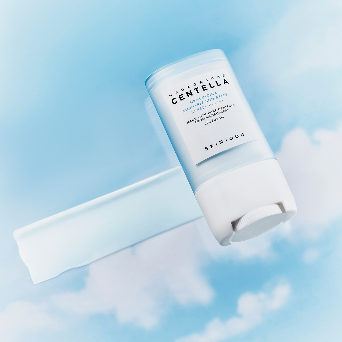 Der Madagascar Centella Hyalu-Cica Silky-Fit Sun Stick von Skin1004 ist vor einem blauen Himmel mit weißen Wolken abgebildet.