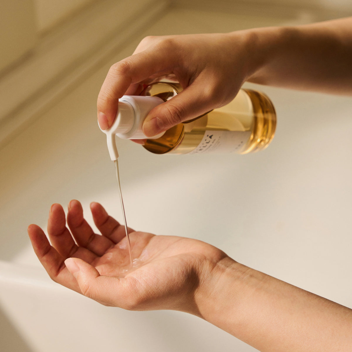 Eine Hand gibt Madagascar Centella Light Cleansing Oil aus einer durchsichtigen Flasche in die Handfläche der anderen Hand.
