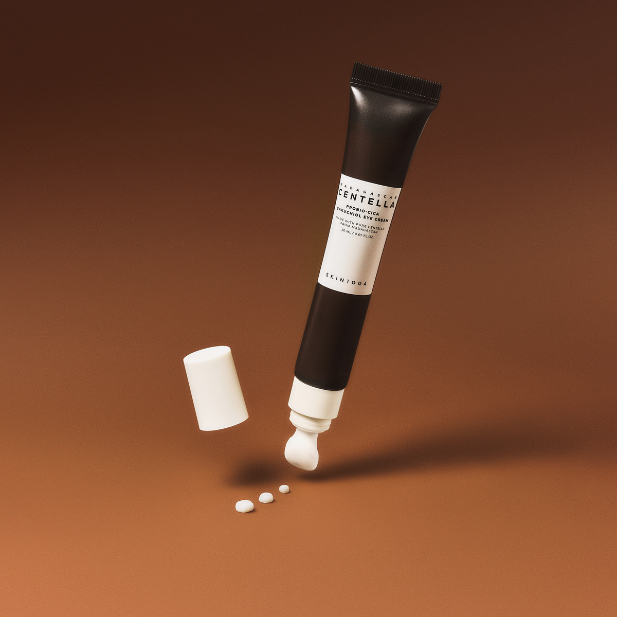 Eine dunkelbraune Tube Probio-Cica Bakuchiol Eye Cream mit weißer Kappe und cremefarbenen Punkten steht auf einem braunen Hintergrund.