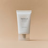 Eine weiße Tube Madagascar Centella Soothing Cream steht aufrecht auf einem beigen Hintergrund.