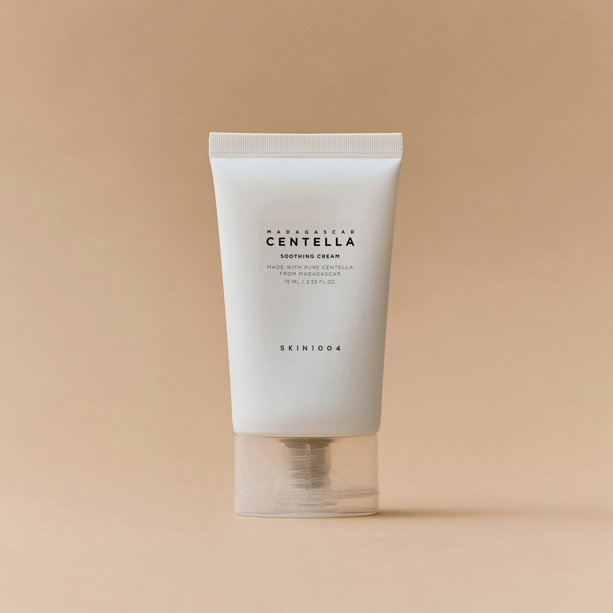 Eine weiße Tube Madagascar Centella Soothing Cream steht aufrecht auf einem beigen Hintergrund.