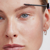 Eine Person trägt das XLASH Xbrow Sensitive Augenbrauenserum mit einem Applikator auf ihre Augenbrauen auf.