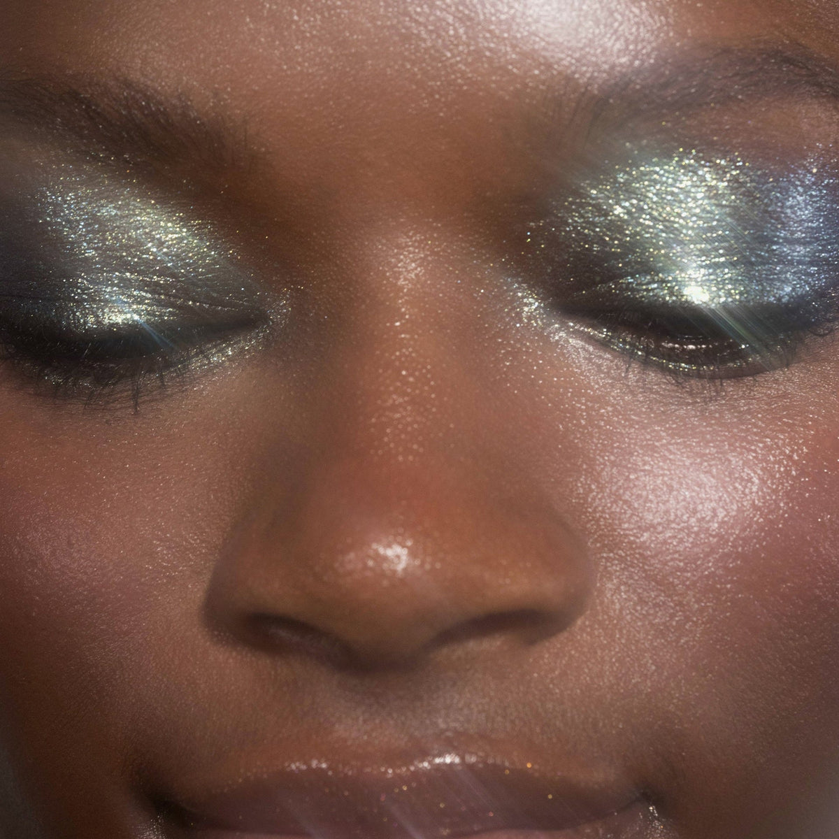 Nahaufnahme des Gesichts einer Frau mit grün-blau glitzerndem Lidschatten Sparkl Tease von LH Cosmetics.