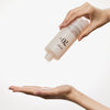 Eine Hand gießt Rice 70 Glow Milky Toner aus einer Flasche auf eine offene Handfläche.