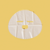 Eine weiße, perforierte Breakout+Aid-Vitamin-C-Maske auf gelbem Hintergrund.