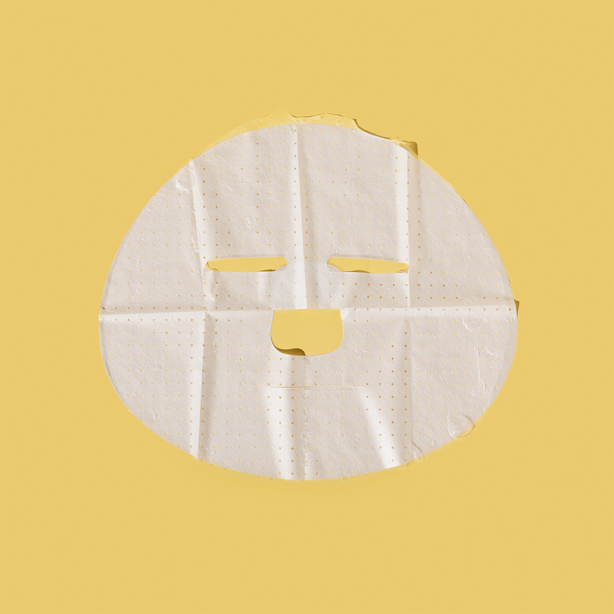 Eine weiße, perforierte Breakout+Aid-Vitamin-C-Maske auf gelbem Hintergrund.