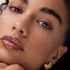 Nahaufnahme eines Gesichts mit glänzenden, braun-beigen Lippen, betont durch Catrice Colour Cushion Juicy Lip Oil für ein elegantes, gepflegtes Finish.