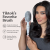 Frau mit dunklen Haaren hält die weiße Miracle Brush x Hairtamin vor hellem Hintergrund mit Text zu Vorteilen der Bürste.