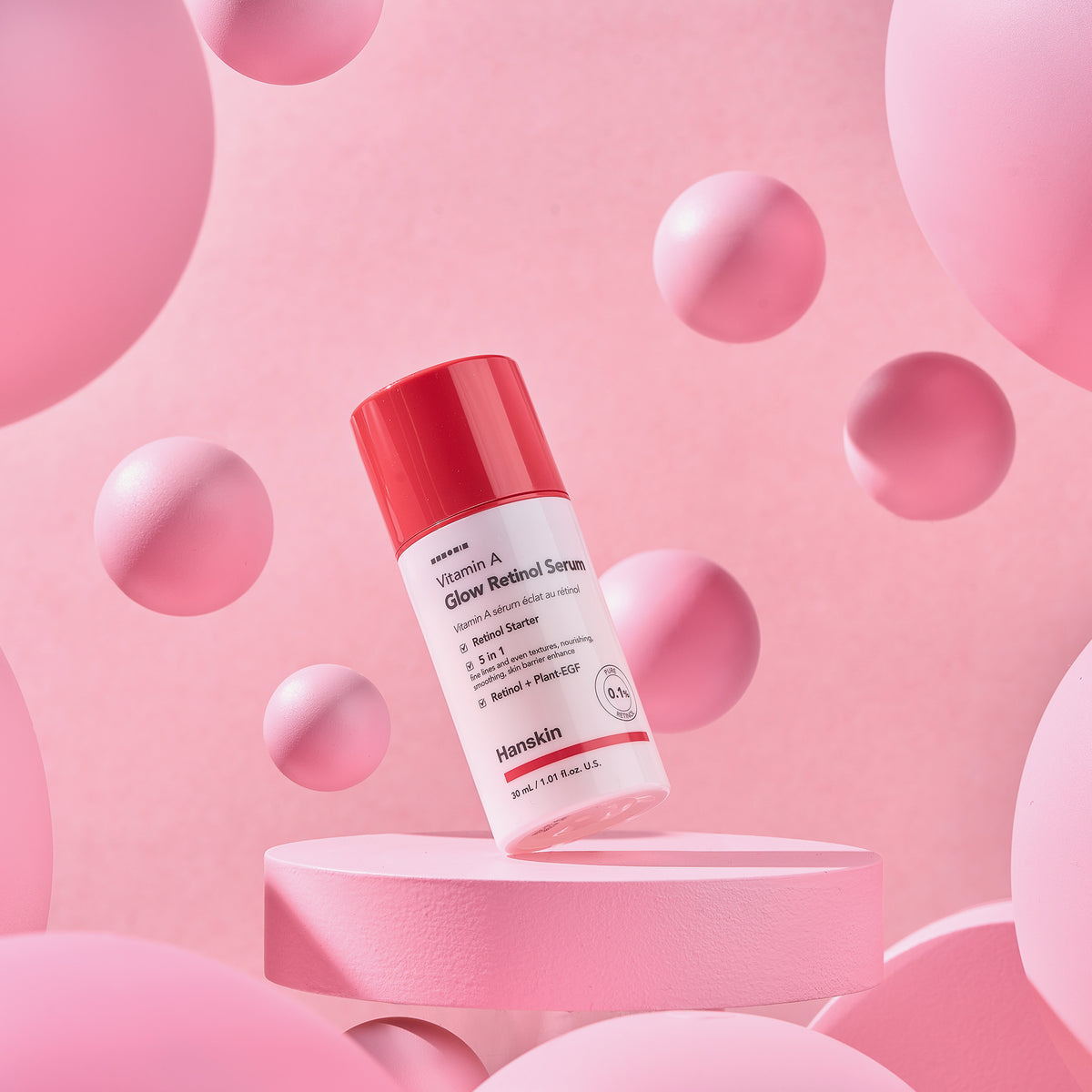 Eine Flasche Vitamin A Glow Retinol Serum, präsentiert auf einer rosa Plattform mit schwebenden rosa Kugeln.