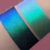 Zwei Muster des Opal Moonstone Loose Multichrome Eyeshadow Clever Clogs mit unterschiedlichen Grundierungen; eins mit der Black Base (Dunkelblau-Grün schimmernd), ein mit der Fix Potion (Türkis-Lila-Grün schimmernd).