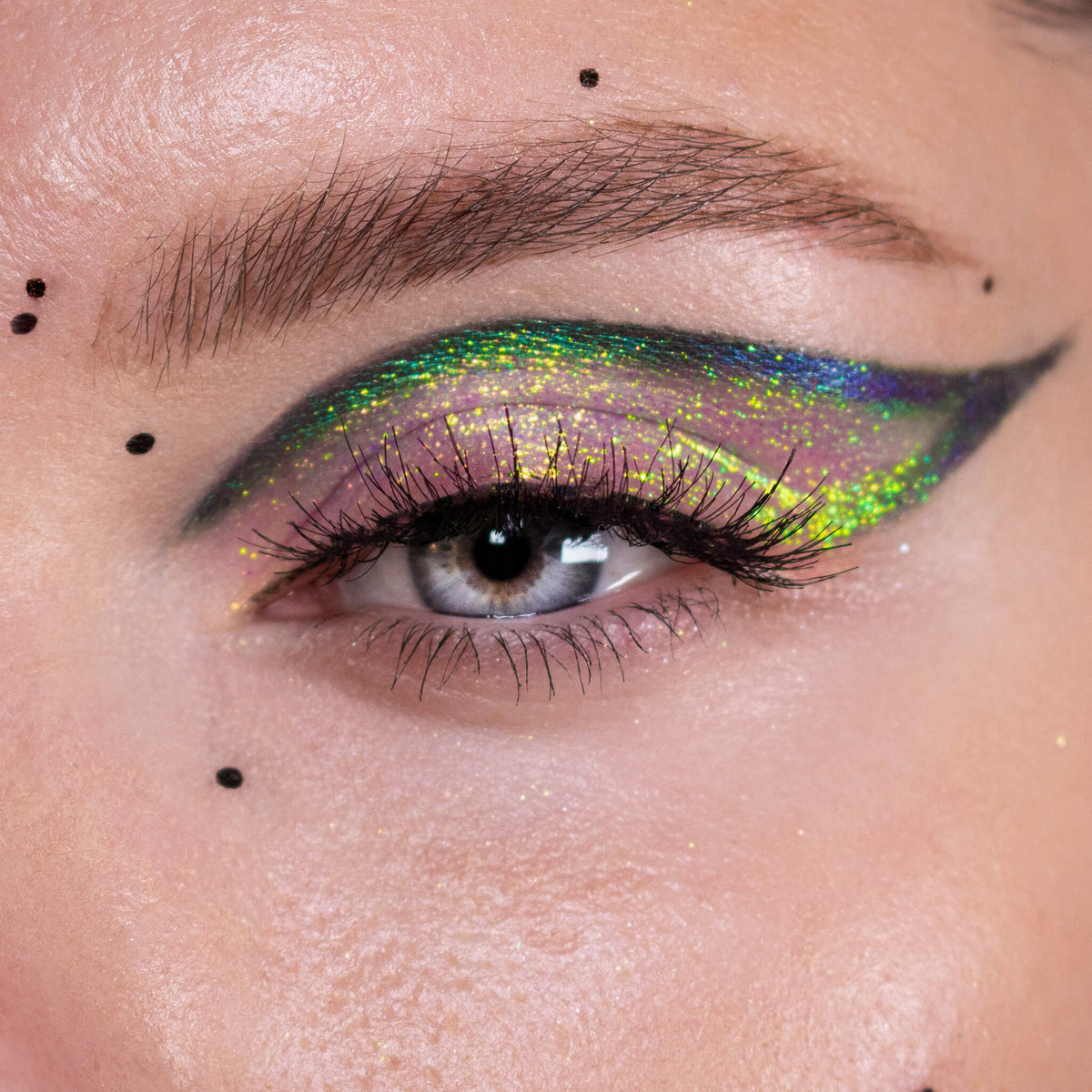Nahaufnahme eines Auges mit dramatischem Eyeliner und gelb-grün schimmerndem Opal Moonstone Loose Multichrome Eyeshadow in Cry Baby.