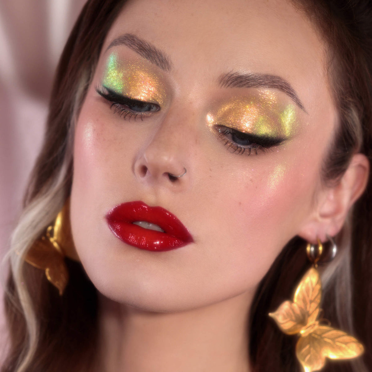 Frau mit dramatischem Eyeliner und glänzenden dunkelroten Lippen trägt gelb-grün schimmernden Opal Moonstone Loose Multichrome Eyeshadow in Sassy Pants auf den Augen.