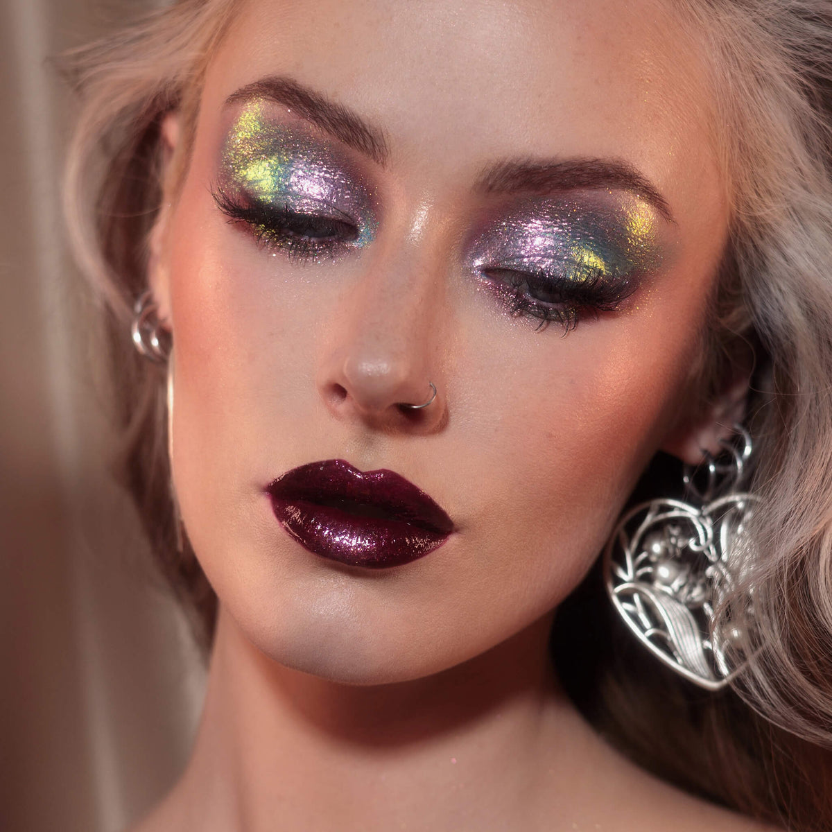 Frau mit dramatischem Eyeliner und glänzenden dunkelroten Lippen trägt lila-blau-grün schimmernden Opal Moonstone Loose Multichrome Eyeshadow in Sleepy Head auf den Augen.
