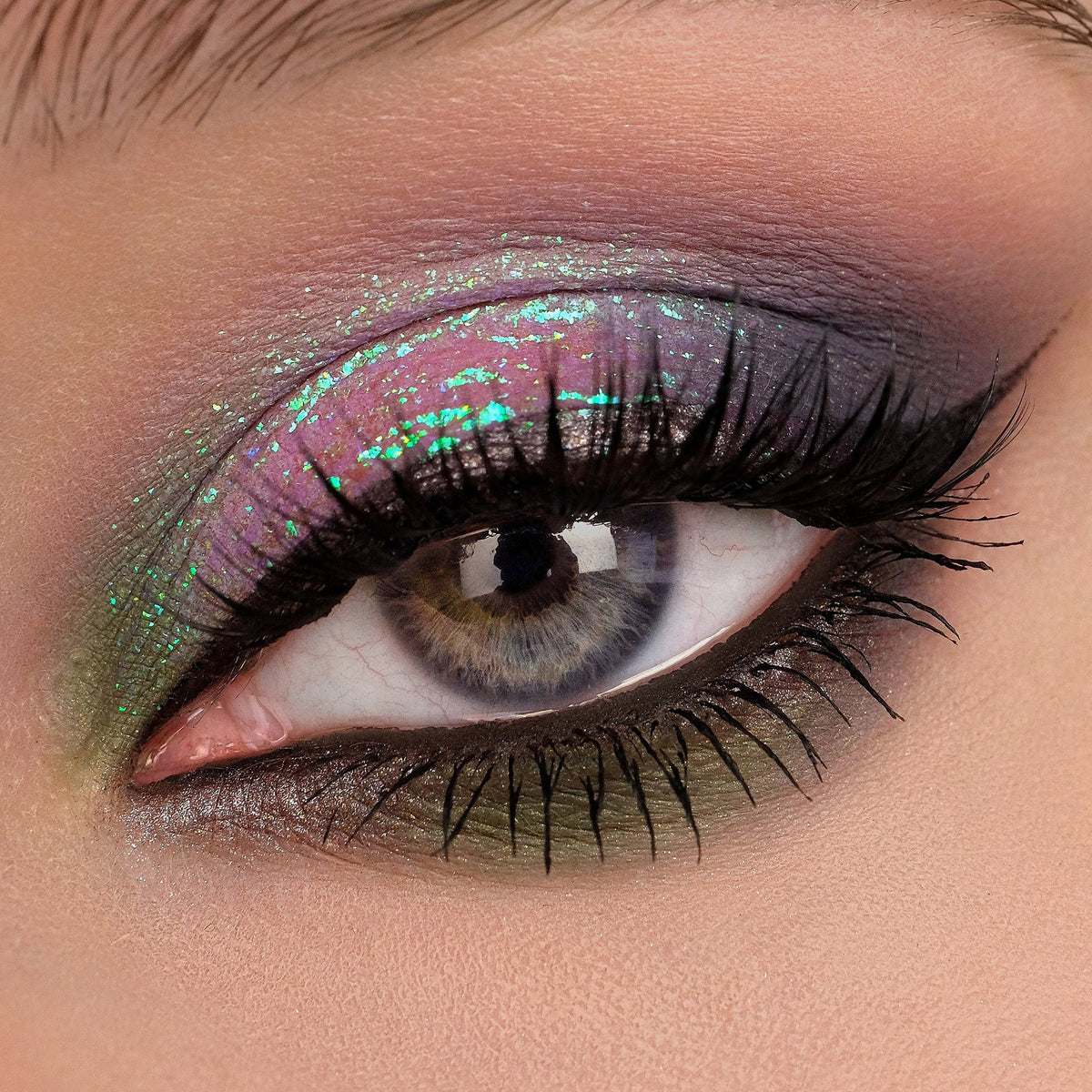 Nahaufnahme eines Auges mit dramatischem Eyeliner und grünlich-türkis schimmerndem Opal Multichrome Loose Eyeshadow in Birdsong.