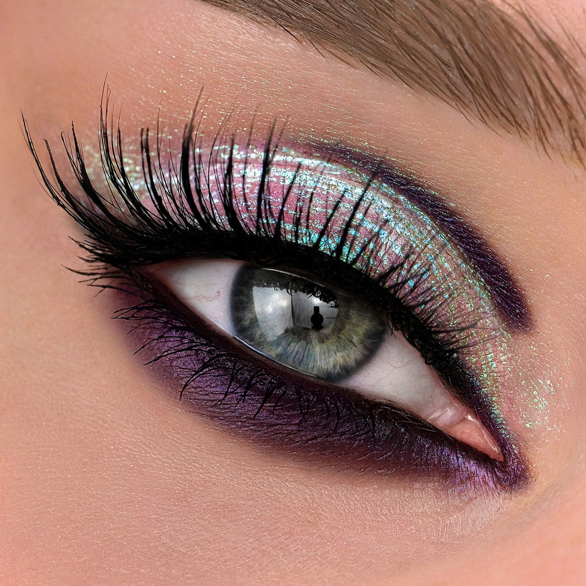 Nahaufnahme eines Auges mit dramatischem lilanen Eyeliner und grünlich-türkis schimmerndem Opal Multichrome Loose Eyeshadow in Chill.