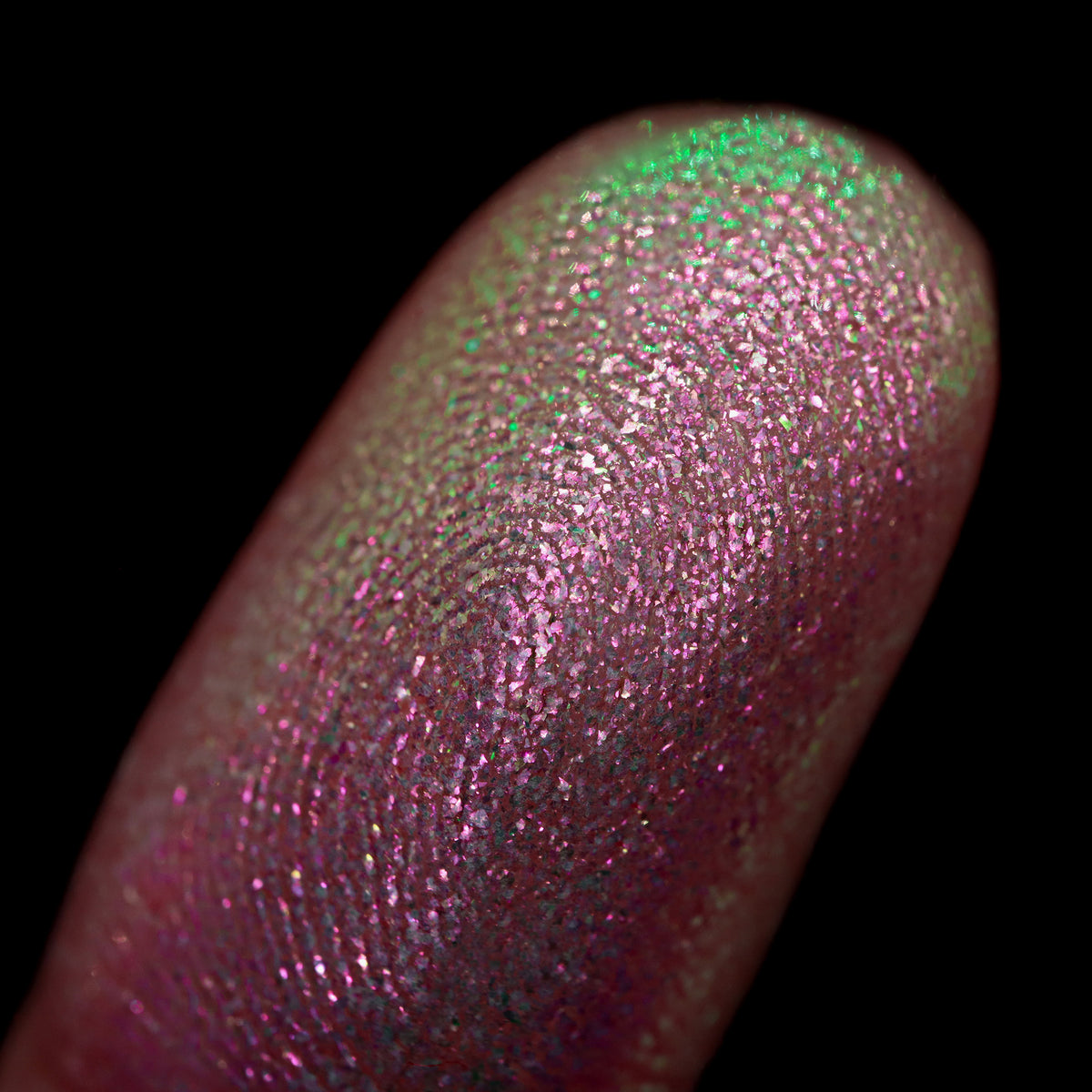 Nahaufnahme einer Fingerspitze, die in den Opal Multichrome Loose Eyeshadow Nightgown getaucht wurde und grün und rosa-bronze glitzert.